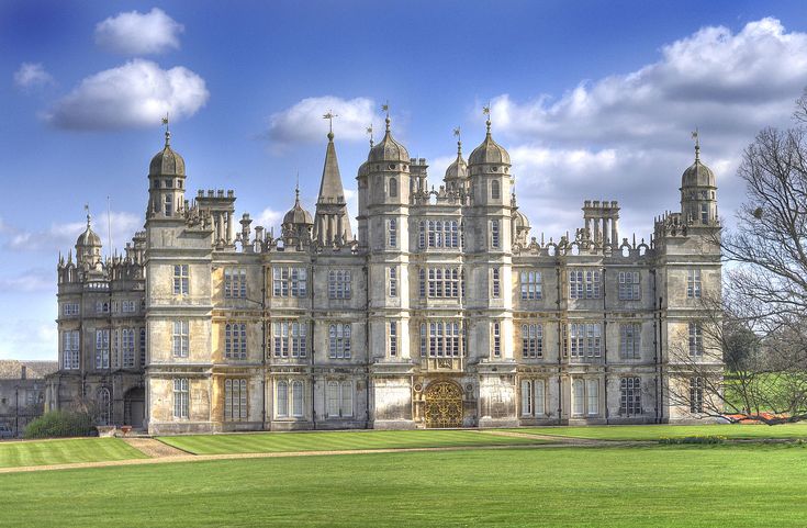 a large building with many windows and towers on top of it's sides in the middle of a green field