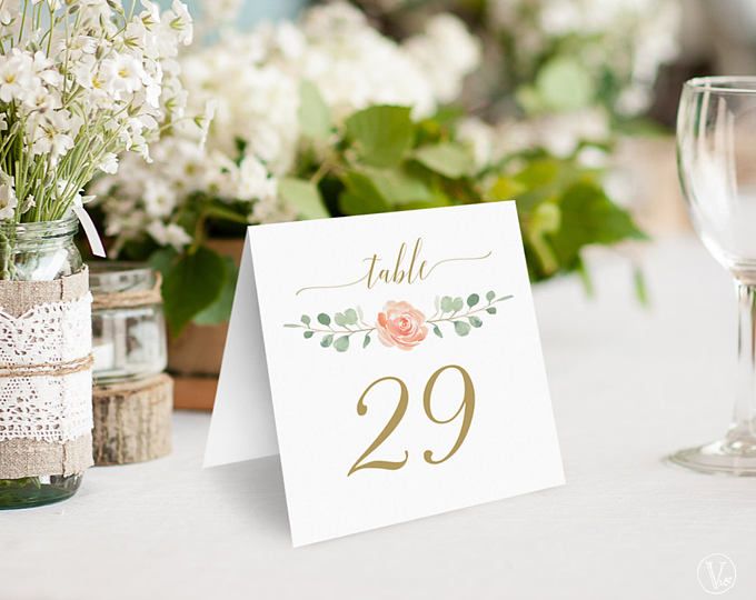 the table numbers are displayed in mason jars and vases with white flowers on them