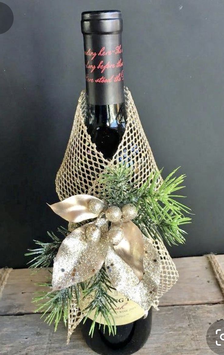 a wine bottle wrapped in burlap with a gold bow and pine cones on top