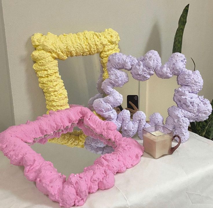 there are three different colored frames on the table next to each other, one is made out of crochet