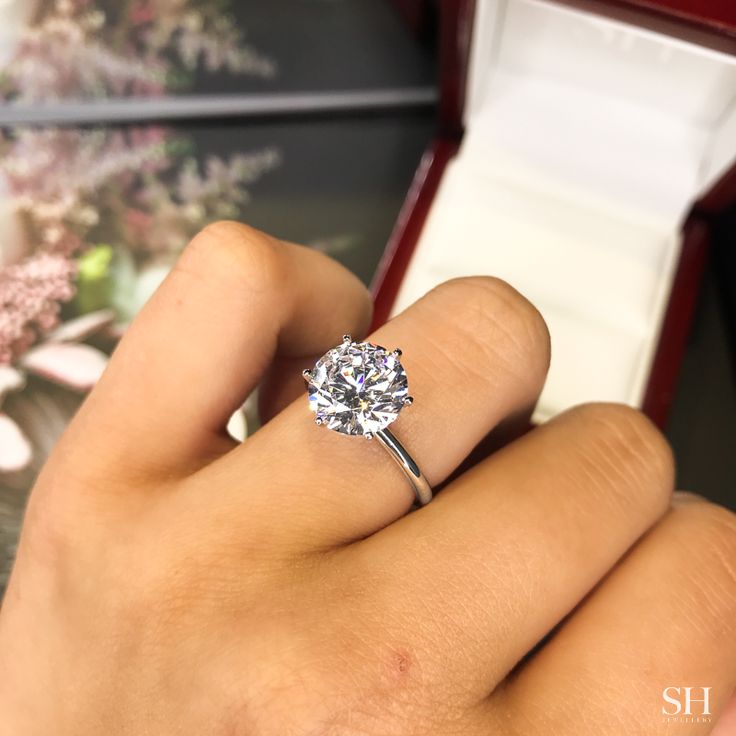 a close up of a person's hand holding a diamond ring