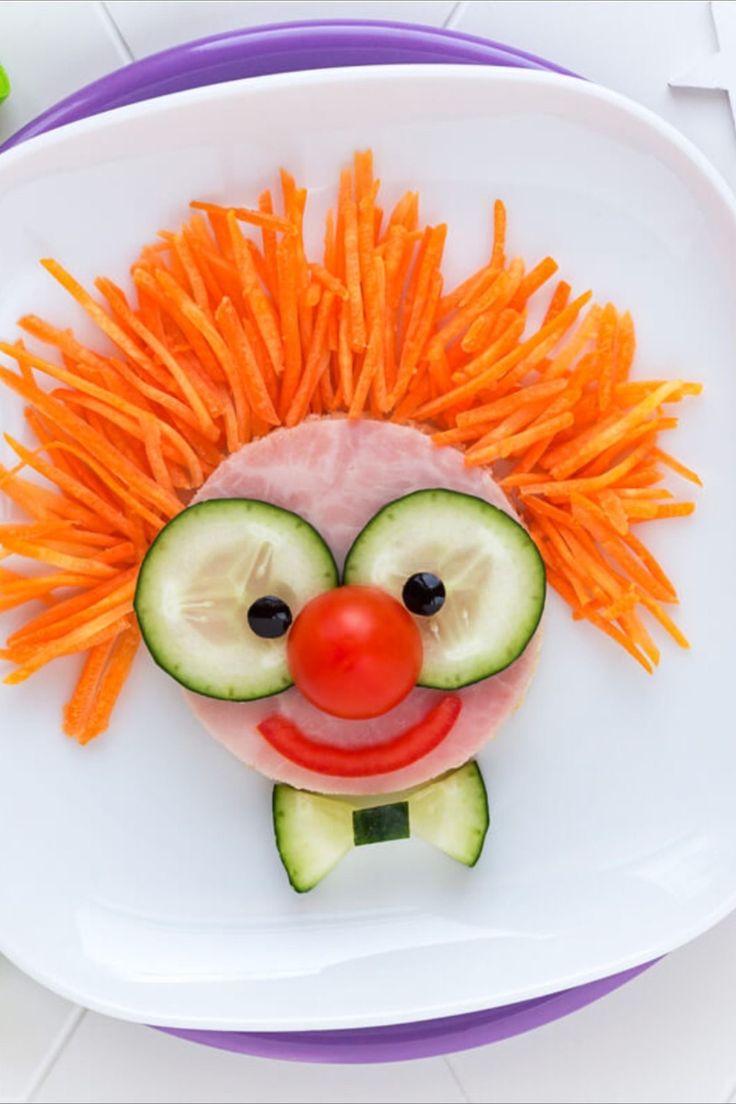 a plate with carrots, cucumber slices and a face made out of vegetables