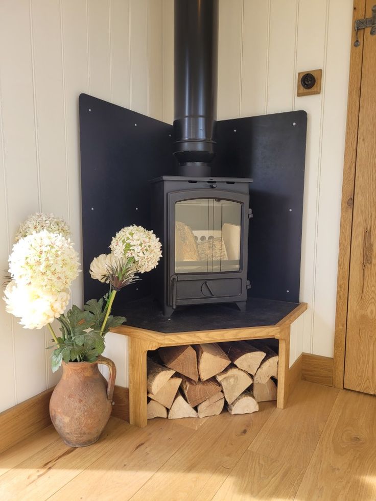 a wood burning stove sitting on top of a wooden floor next to a vase filled with flowers