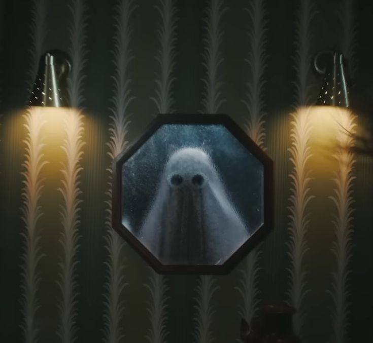 the reflection of two ghost figures in a mirror on a wall with lights behind them