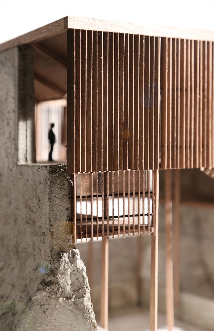 a wooden structure sitting on top of a cement wall next to a small black figure