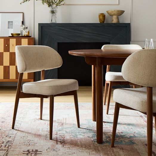 two chairs and a table in a room with a rug on the floor next to it