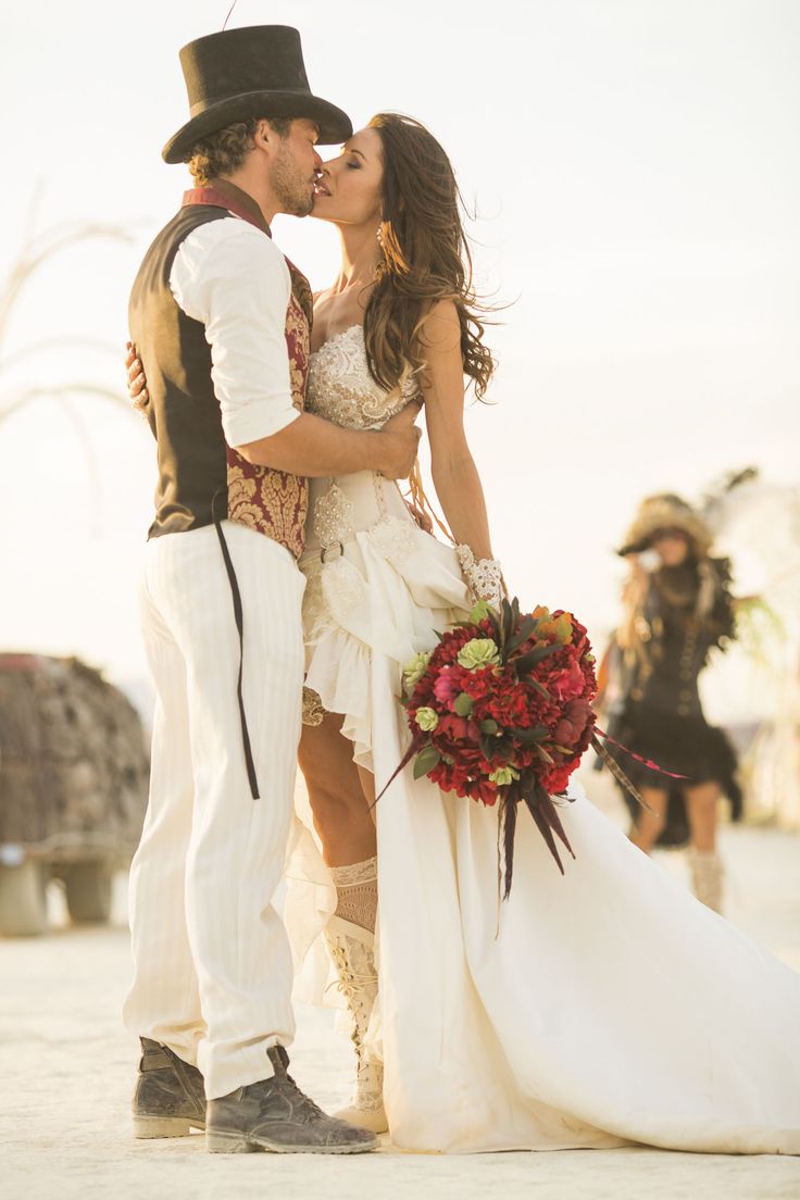 a bride and groom kissing on the beach