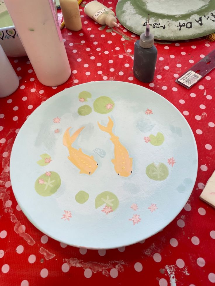 a plate with two fish on it sitting on a red table cloth next to other items