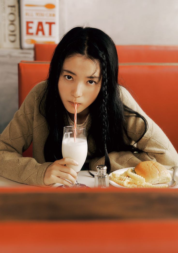 a woman sitting at a table with a glass of milk and food in front of her