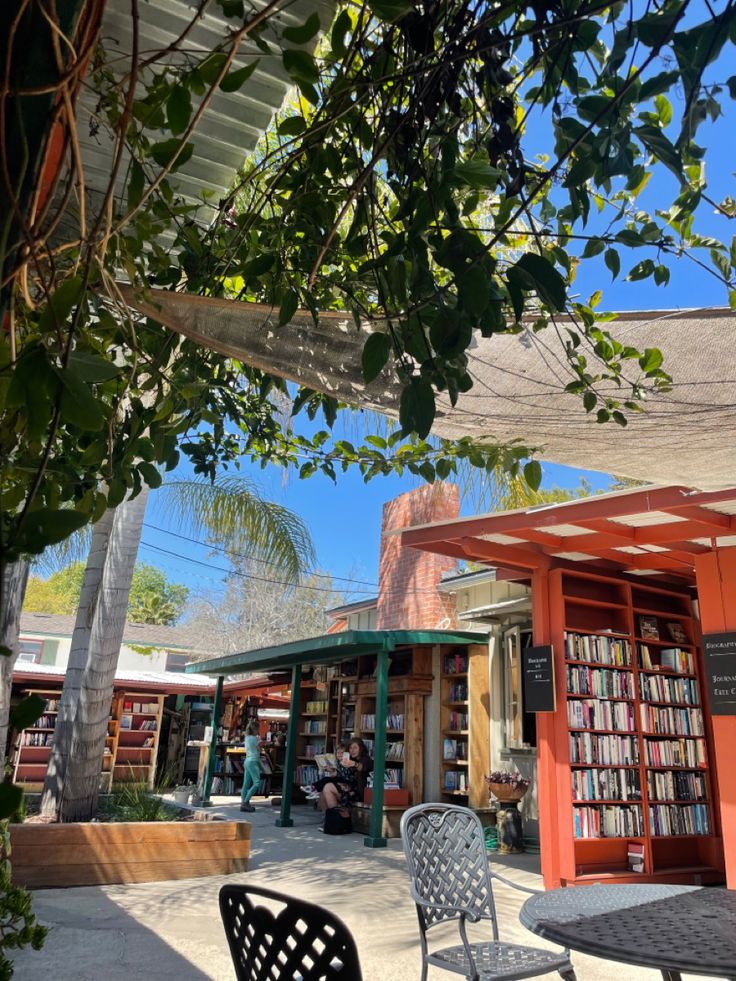 an outdoor area with tables, chairs and bookshelves