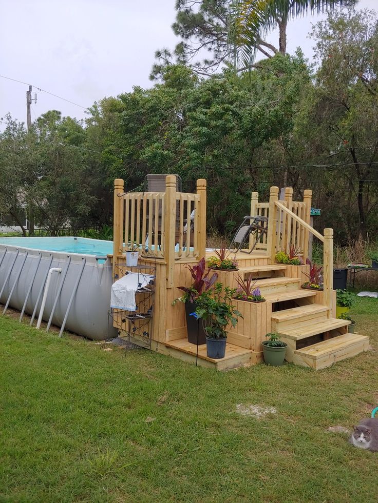 a wooden deck next to a swimming pool with plants and potted plants on it