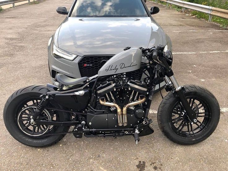 a motorcycle parked next to a car in a parking lot with no one around it