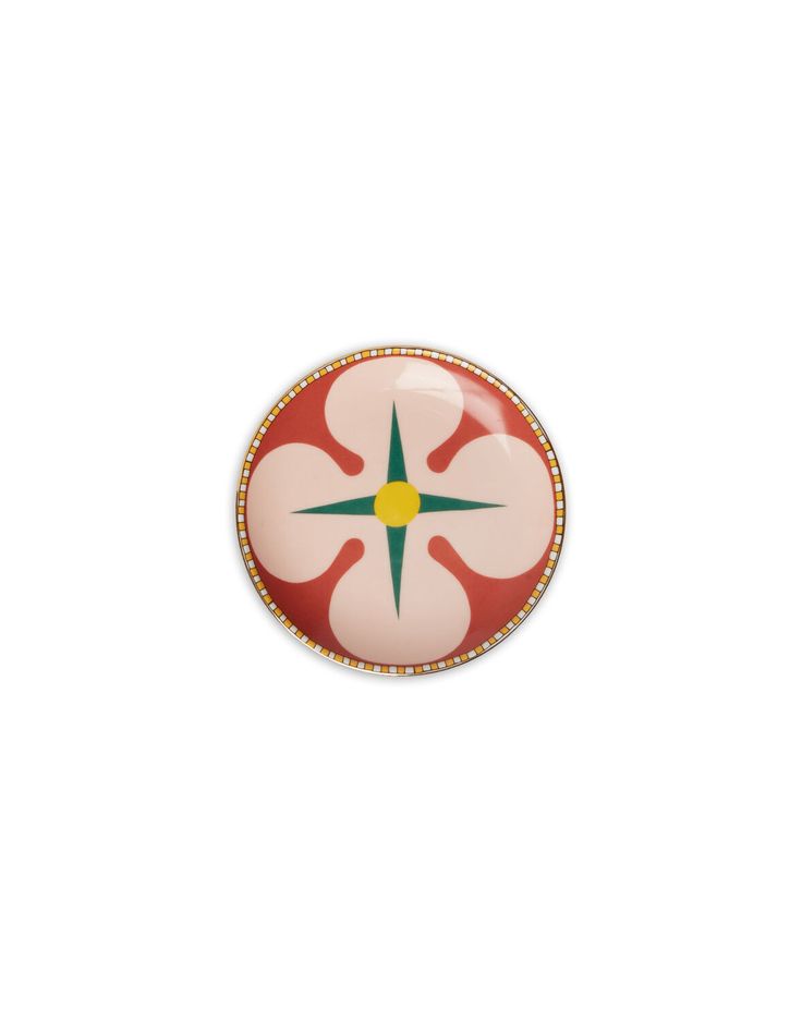 a red and white button with a green star on the center, sitting in front of a white background