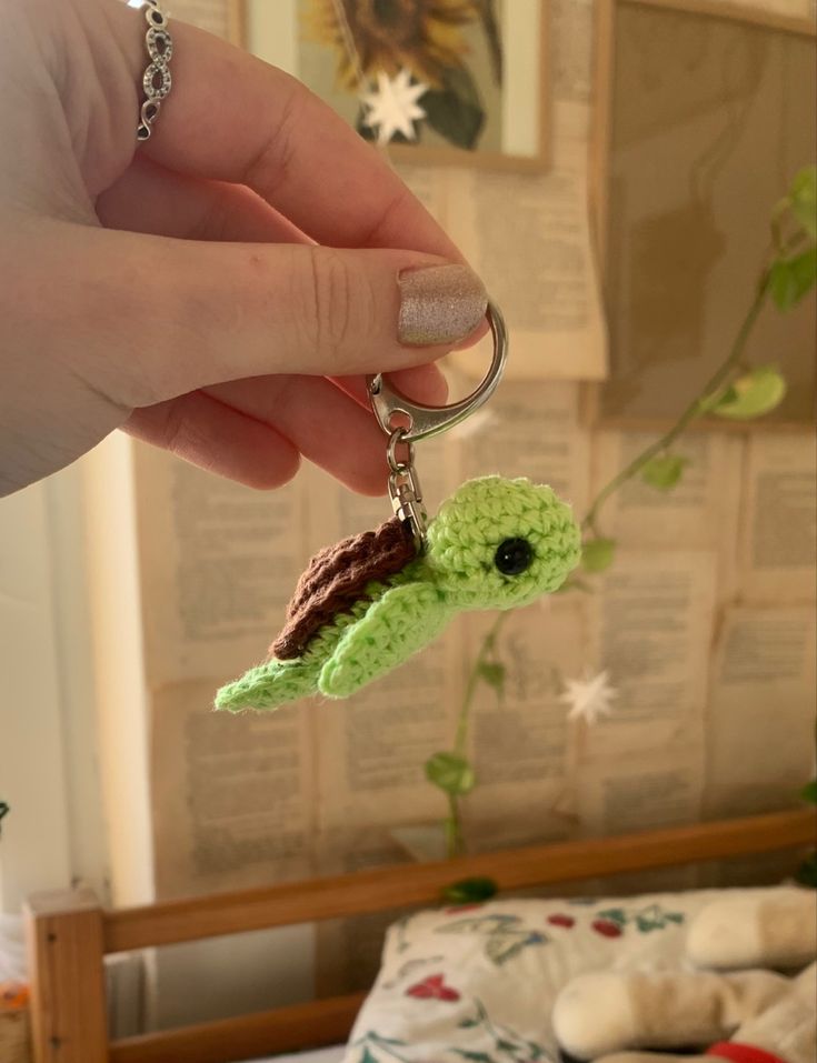 a hand holding a keychain with a tiny turtle on it