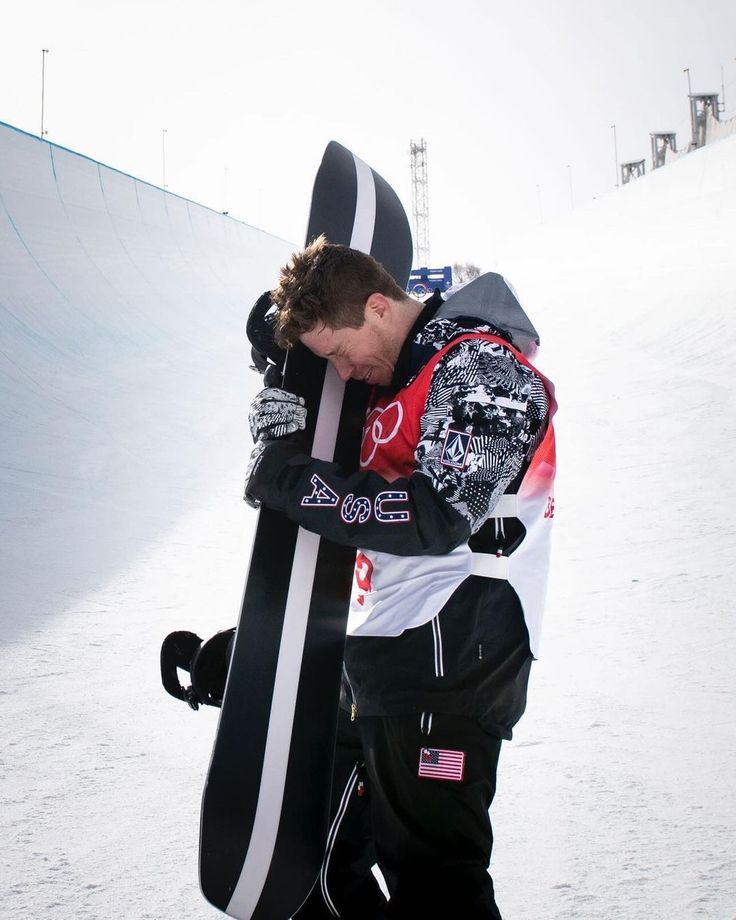 a snowboarder is hugging his board on the slope