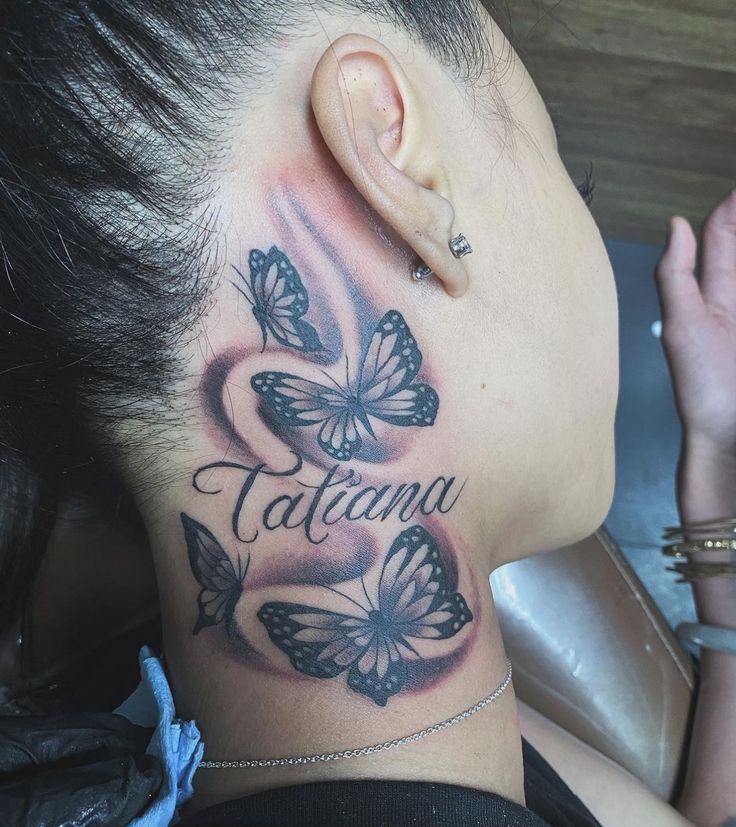 a woman's neck with butterflies and the word tattoma tattooed on it