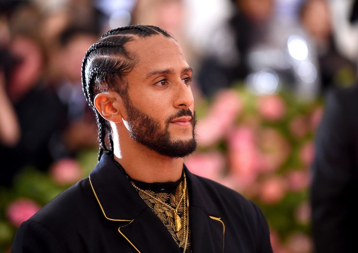 a man with dreadlocks on his head and wearing a black shirt is looking off to the side