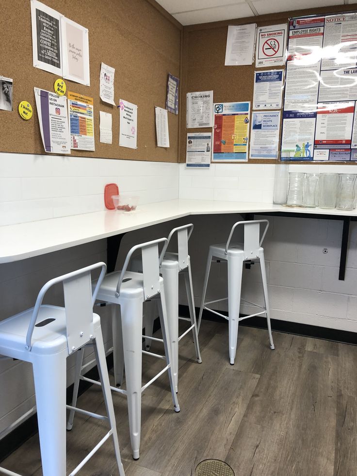 there are four white stools at the counter in this office break - up area