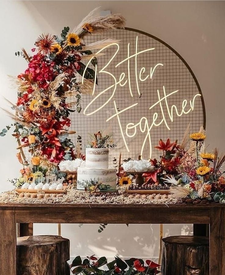 a table topped with a cake and flowers next to a sign that says better together