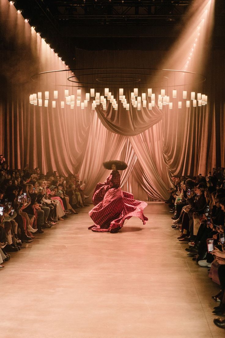 a woman in a red dress and sombrero walks down the runway at a fashion show