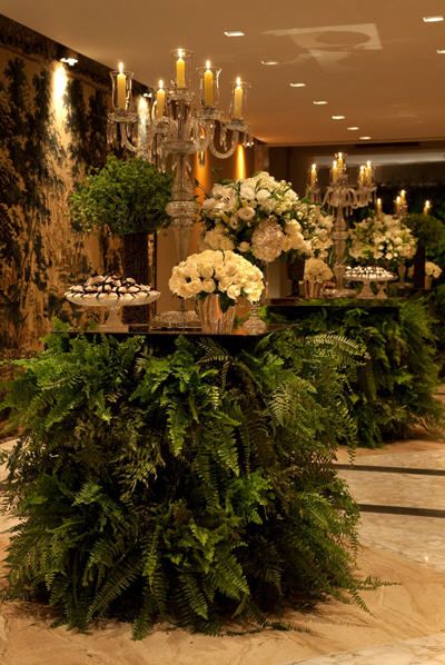 a table with flowers and candles on it in the middle of a room filled with people