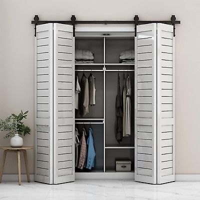 an open white closet with clothes hanging on the doors and two stools next to it