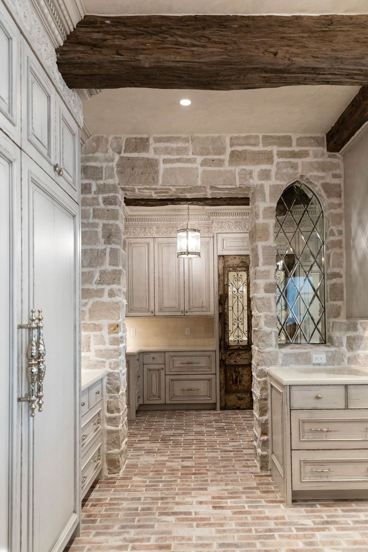 a large kitchen with stone walls and flooring in an old - fashioned style home