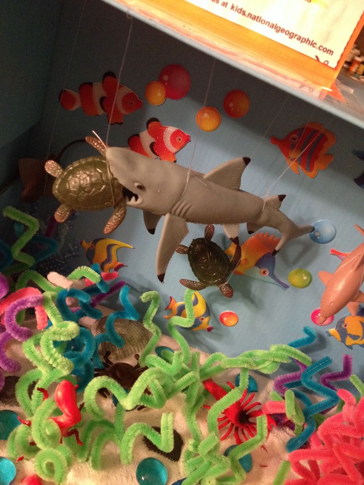 an assortment of plastic toys including a shark and other sea creatures are on display in a box