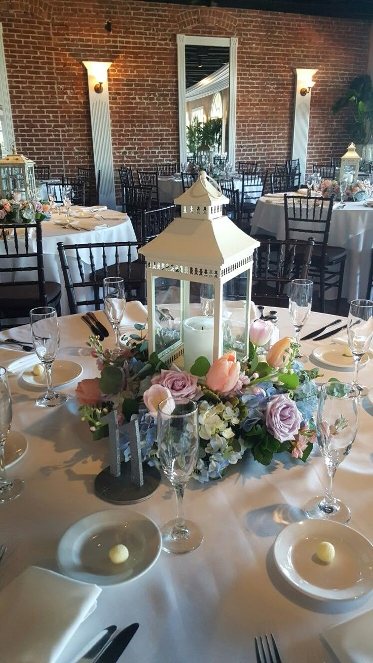 the table is set with white plates, silverware and pink flowers in vases