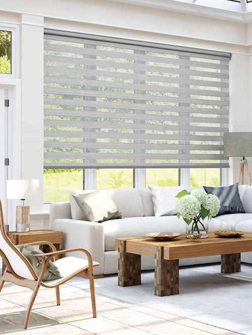 a living room filled with white furniture and lots of windows covered in roman blind shades