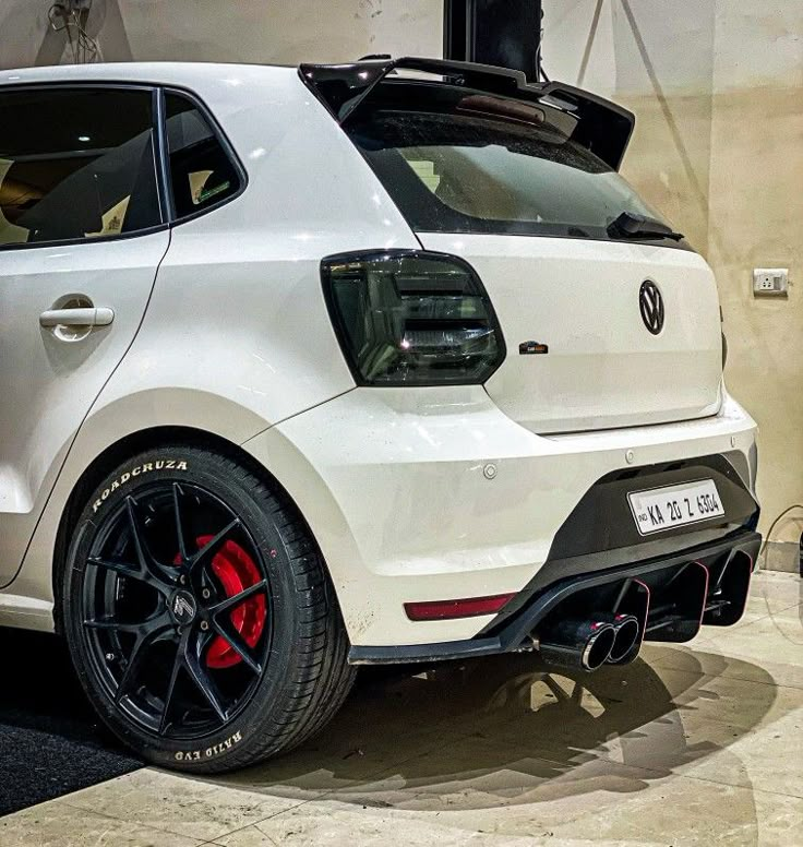 the rear end of a white vw golf gtr with red brake pads and black rims