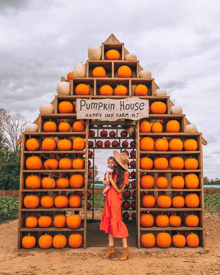 a woman standing in front of a pumpkin house