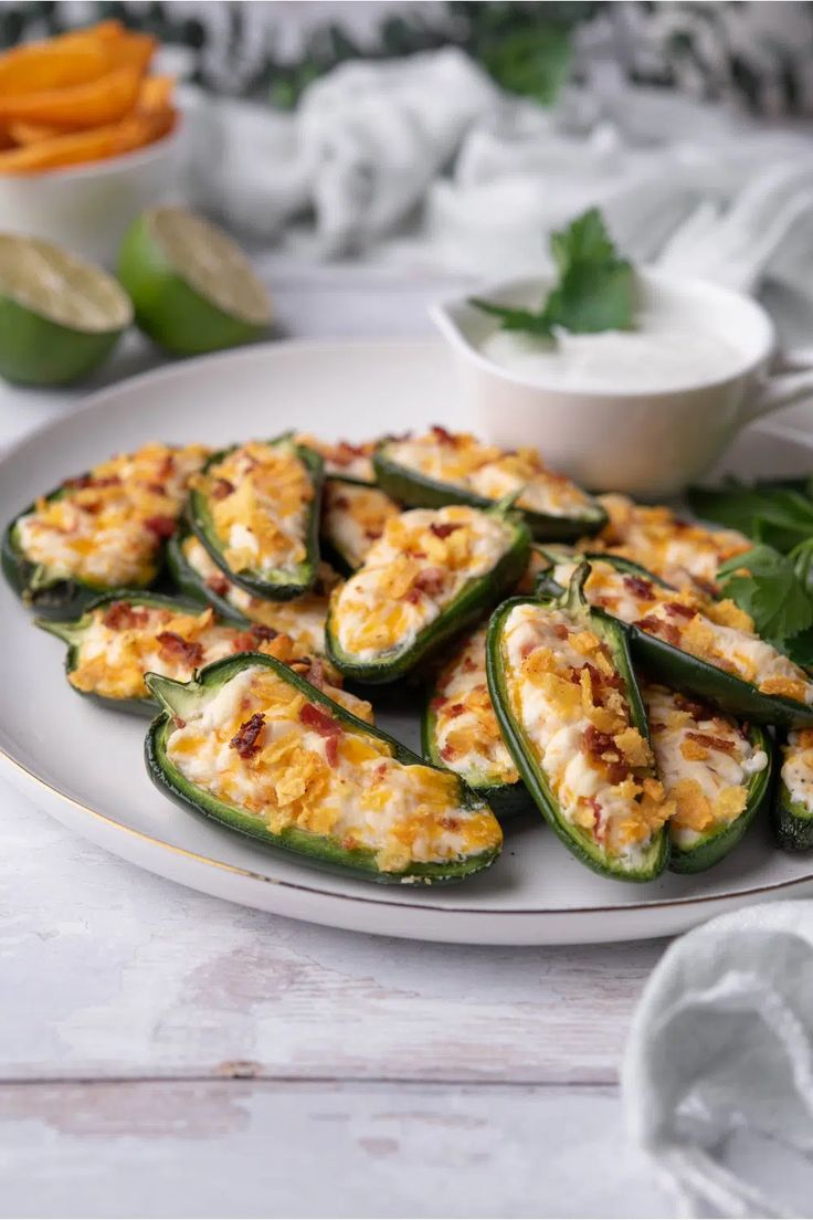 stuffed jalapenos on a white plate with some dipping sauce in the background