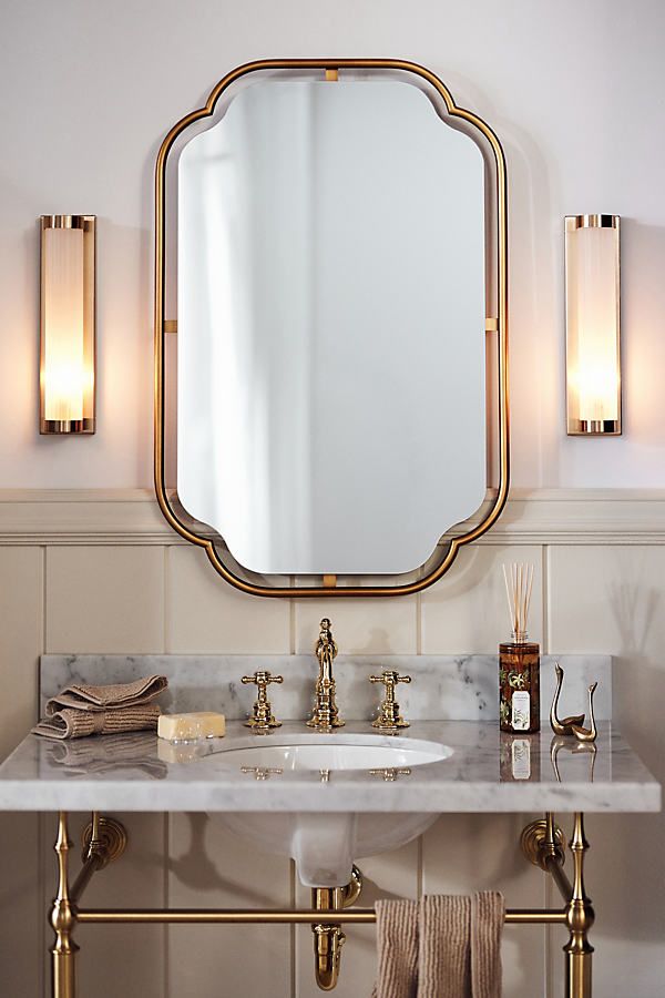 a bathroom sink with a mirror above it and two lights on the wall behind it