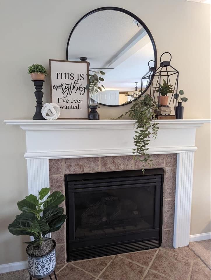 a fireplace with a mirror and potted plants on top