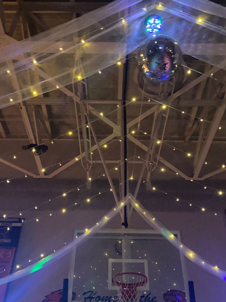 the inside of a basketball court with lights and net hanging from it's ceiling