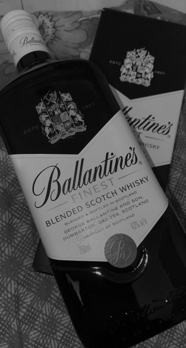 two bottles of ballantine's blended scotch whisky sitting on a bed in black and white