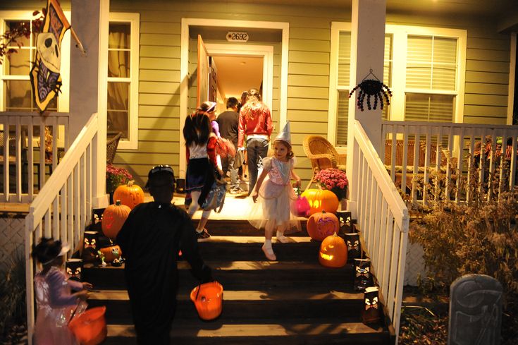 a group of people standing on the steps of a house decorated for halloween