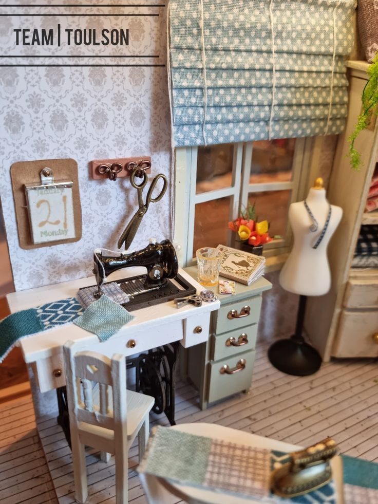 a doll house with a sewing machine and table in the corner, next to a pair of chairs