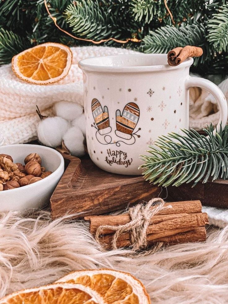 an orange slice is sitting next to a mug and cinnamons on a fur rug