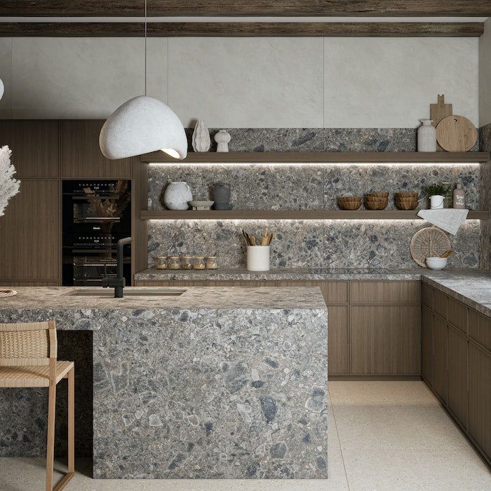 a large kitchen with marble counter tops and wooden cabinetry, along with two chairs