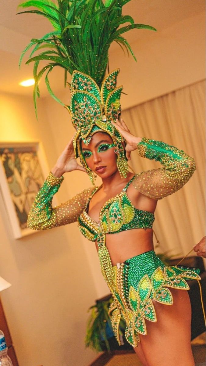 a woman in a green and gold costume posing for the camera with her hands on her head