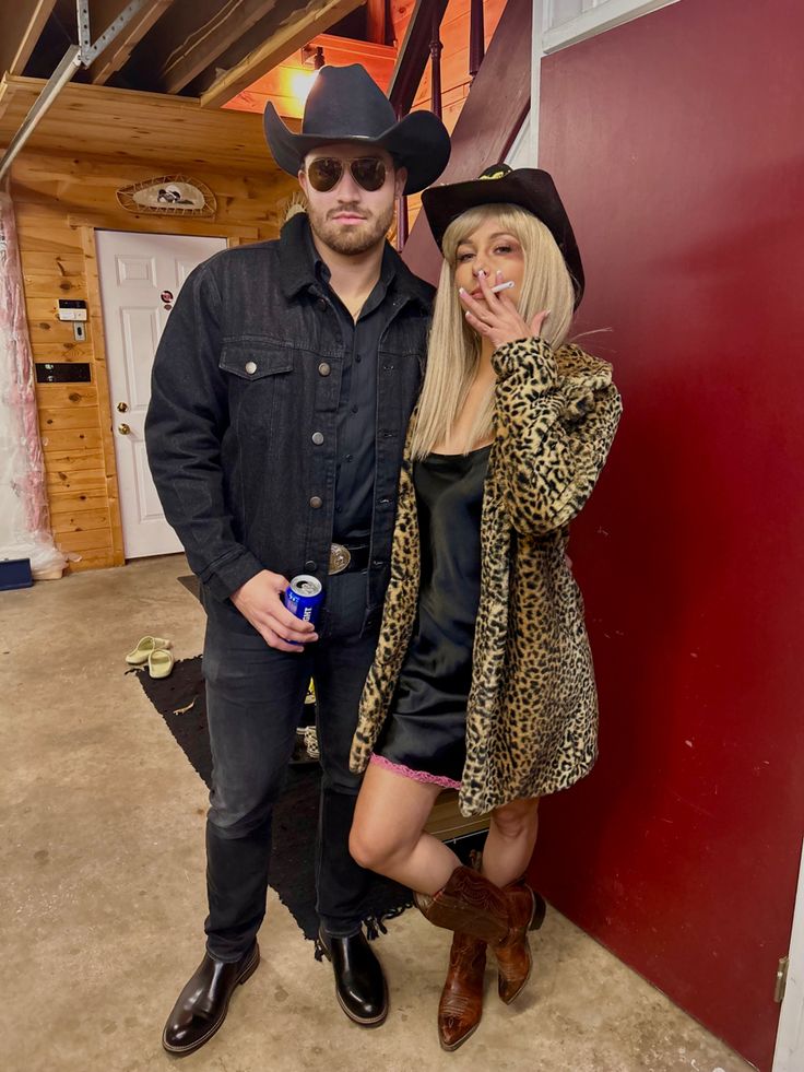 a man and woman in cowboy hats posing for the camera with one holding a beer