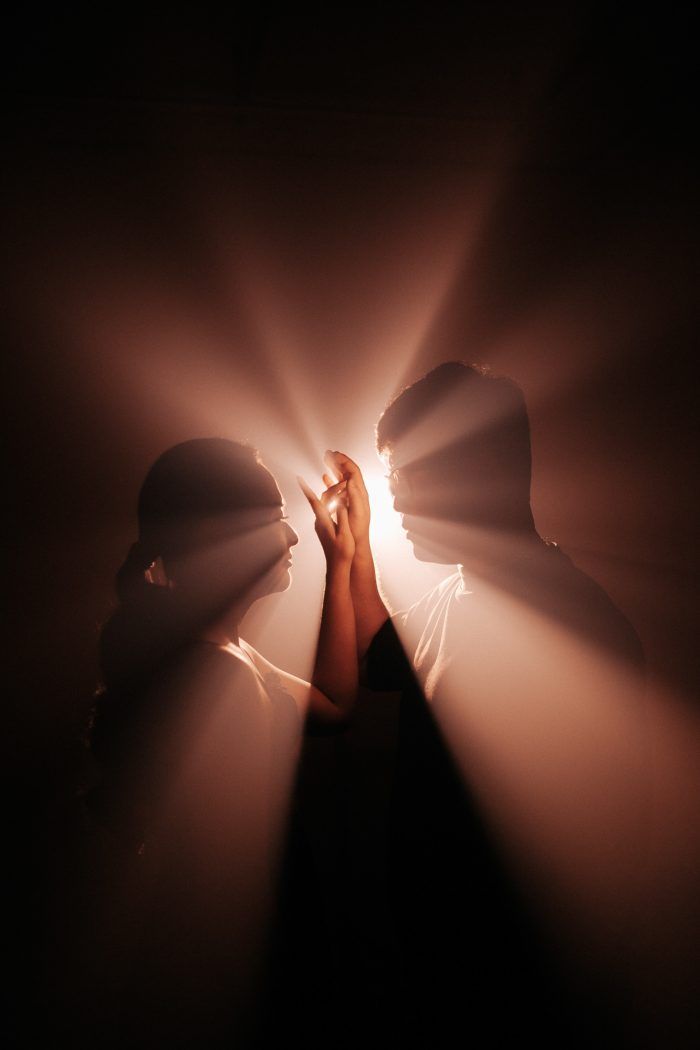 two people standing in the dark with their hands together