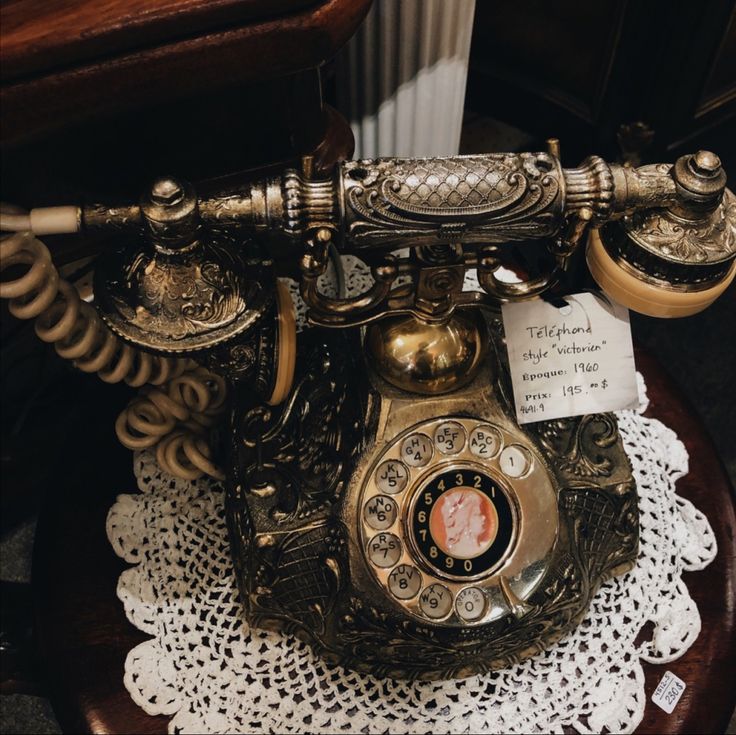 an old fashioned phone sitting on top of a wooden table next to a white doily