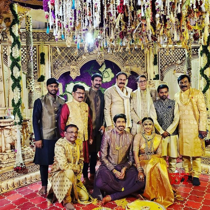 a group of people standing next to each other in front of a decorated stage with chandelier