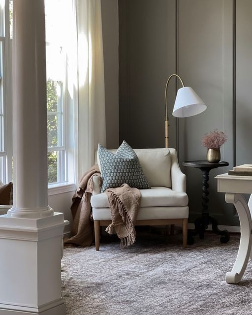 a living room filled with furniture and a lamp on top of a wooden table next to a window