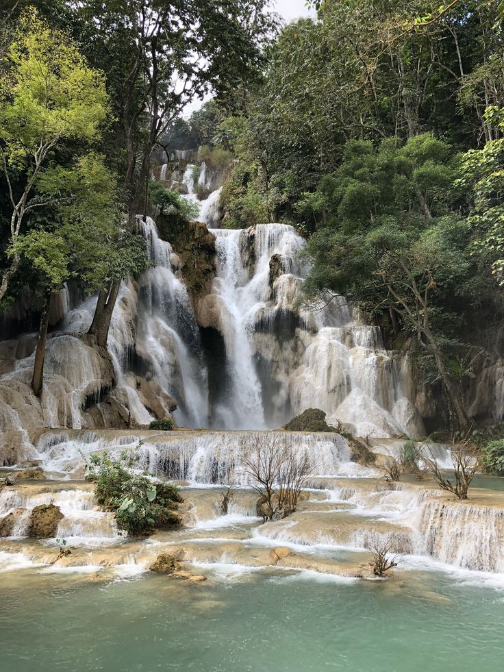 the waterfall is surrounded by green trees and blue water