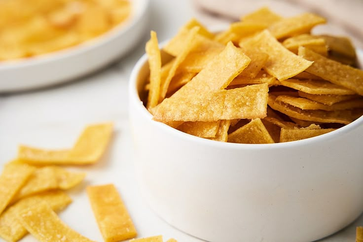 a bowl filled with cheetos sitting on top of a white counter next to another bowl