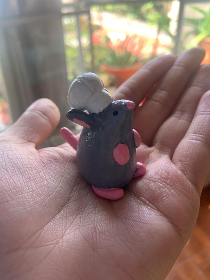 a hand holding a tiny toy mouse in it's palm